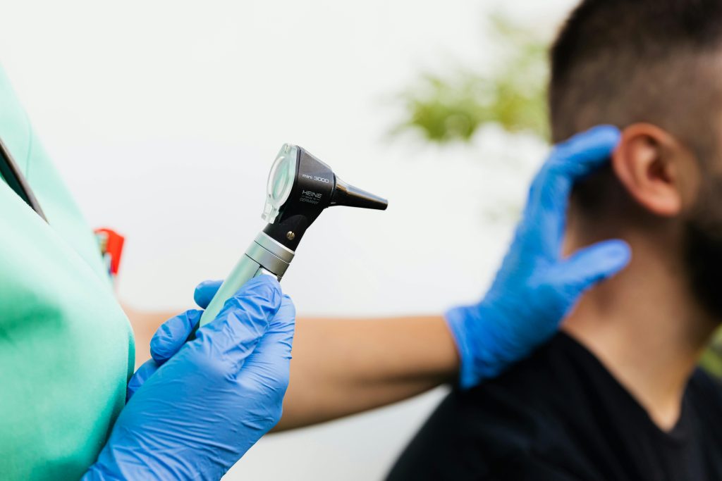 Home Healthcare professional examining patient's ear with an otoscope in a clinical setting.
